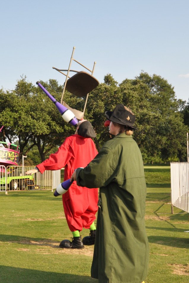 Zerp balancing a chair while Badger juggles clubs